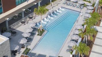 Una piscina al aire libre, sombrillas, sillones reclinables de piscina