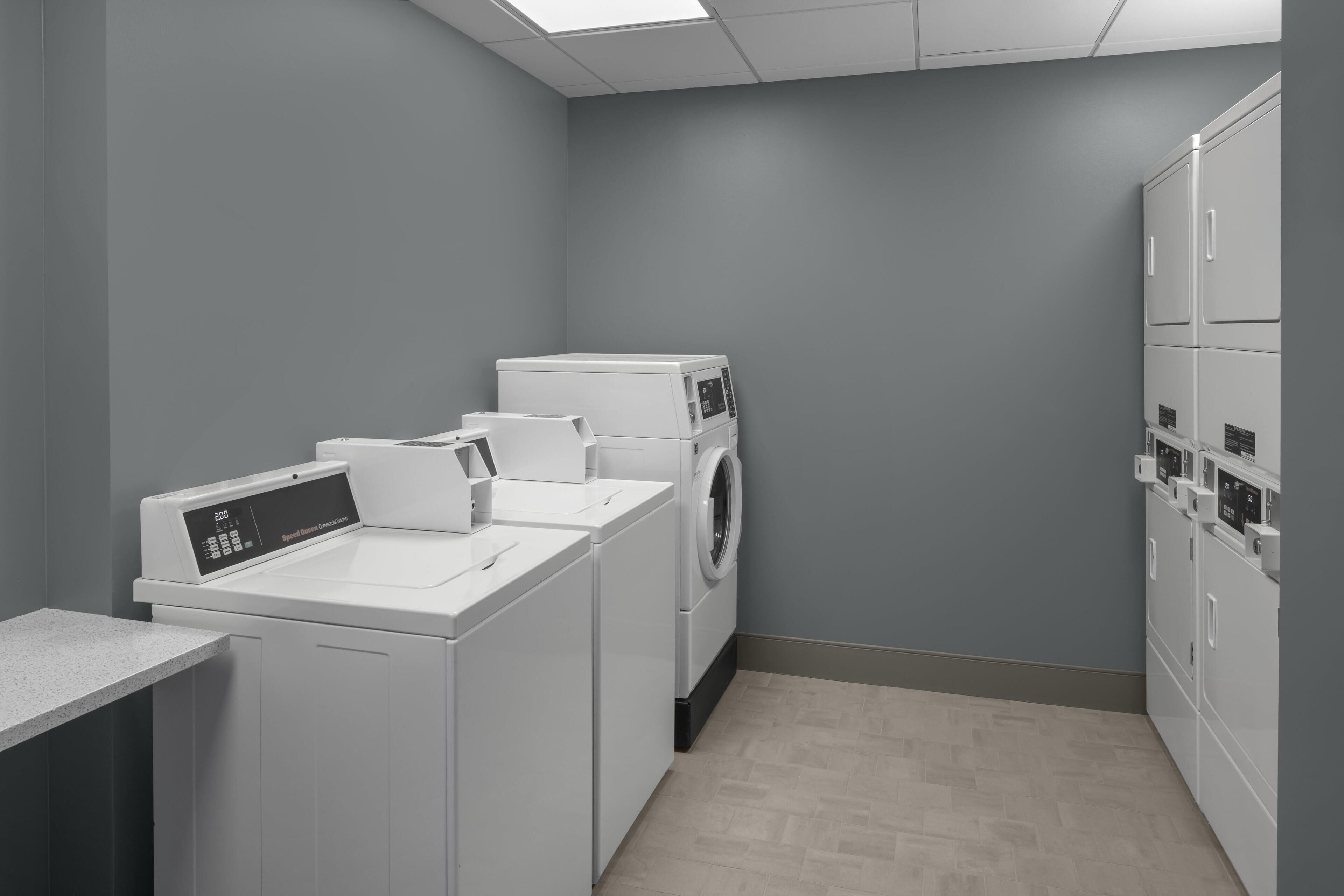 A laundry room with a washing machine, dryer, and stacked cabinets.