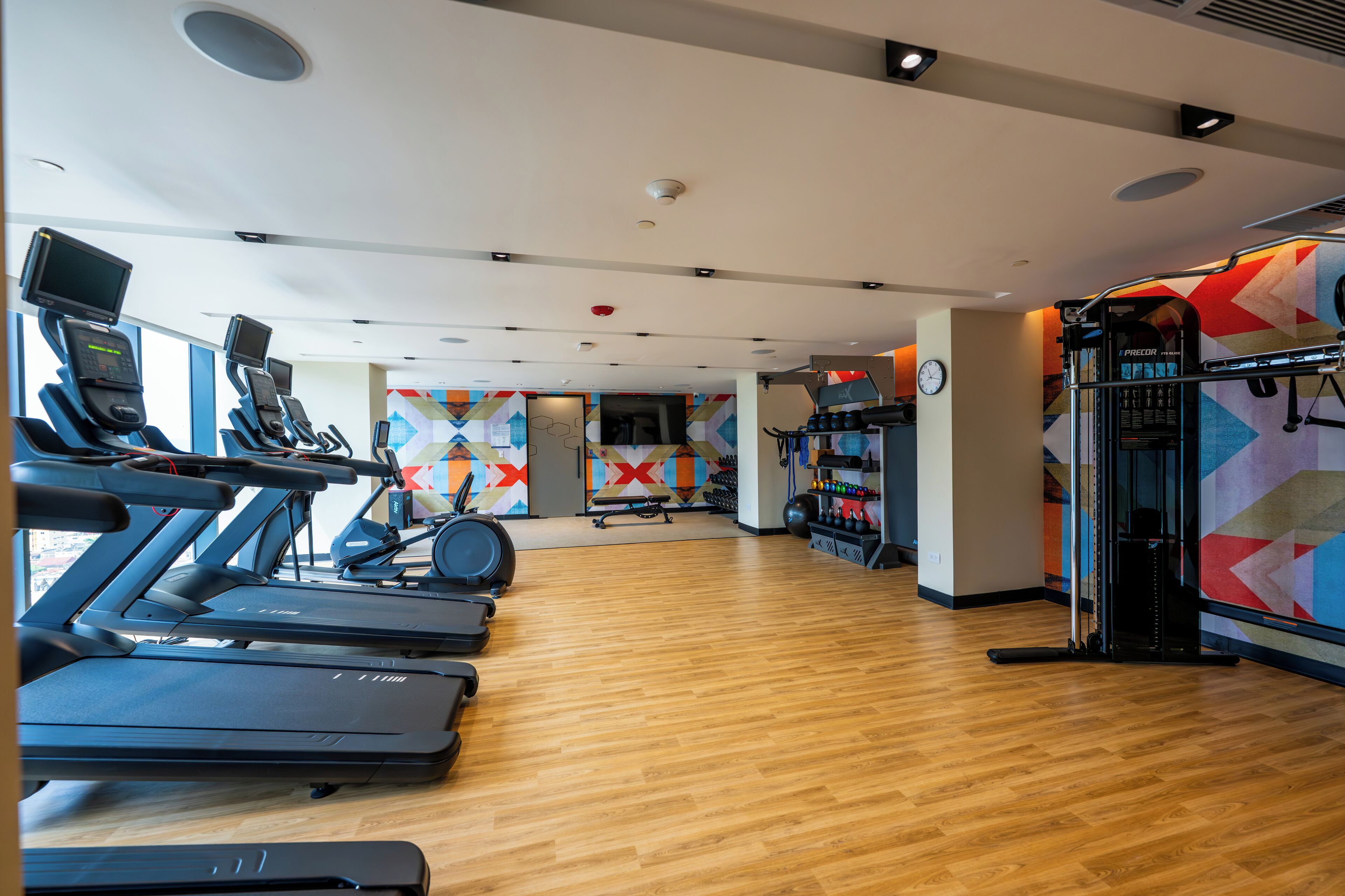 Un gimnasio con cintas de correr, bicicletas estáticas y máquinas de pesas.