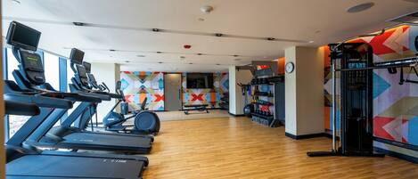 Un gimnasio con cintas de correr, bicicletas estáticas y máquinas de pesas.