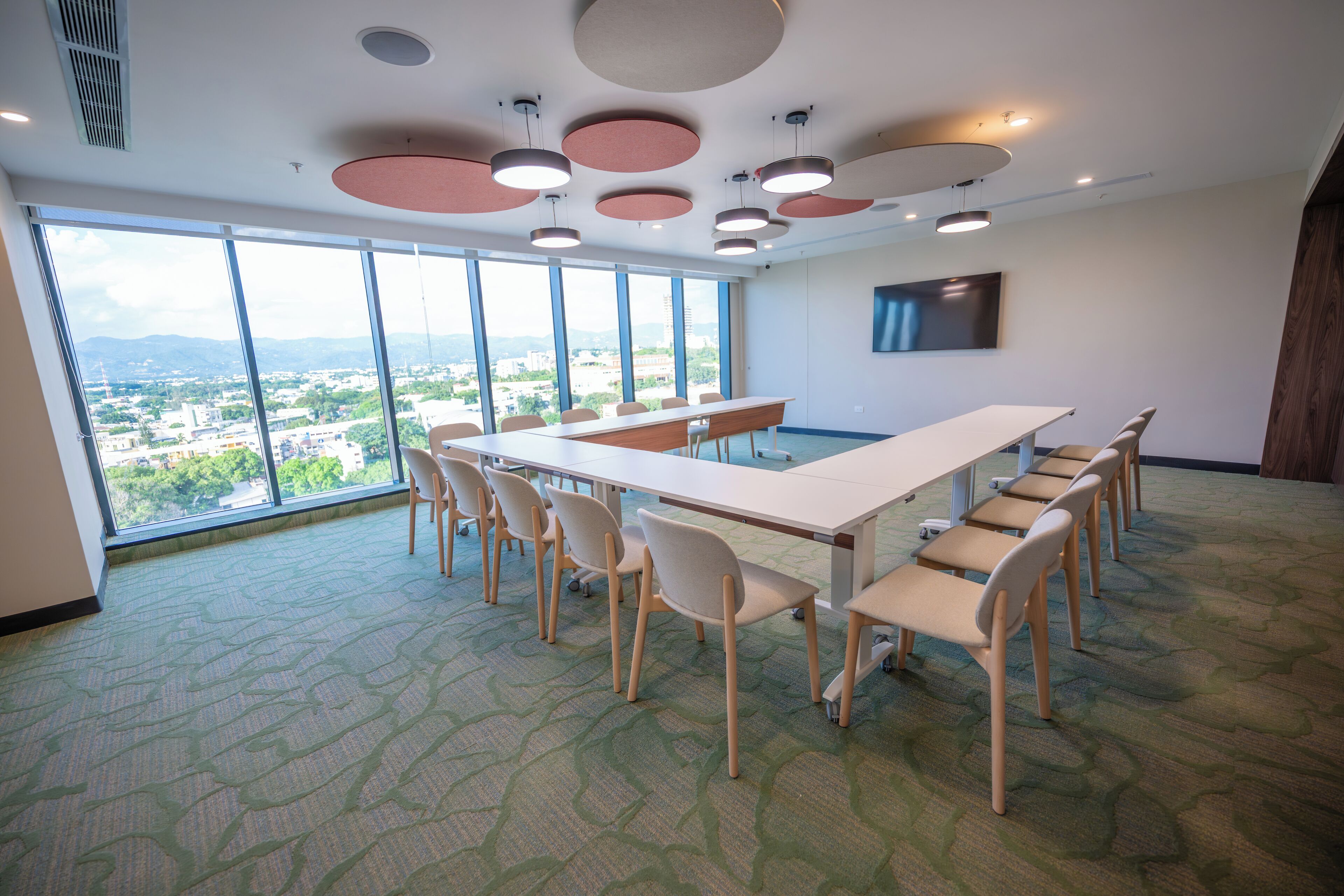 Une salle de conférence dotée d’une grande table, de chaises et offrant une vue sur le paysage urbain grâce à de larges fenêtres.