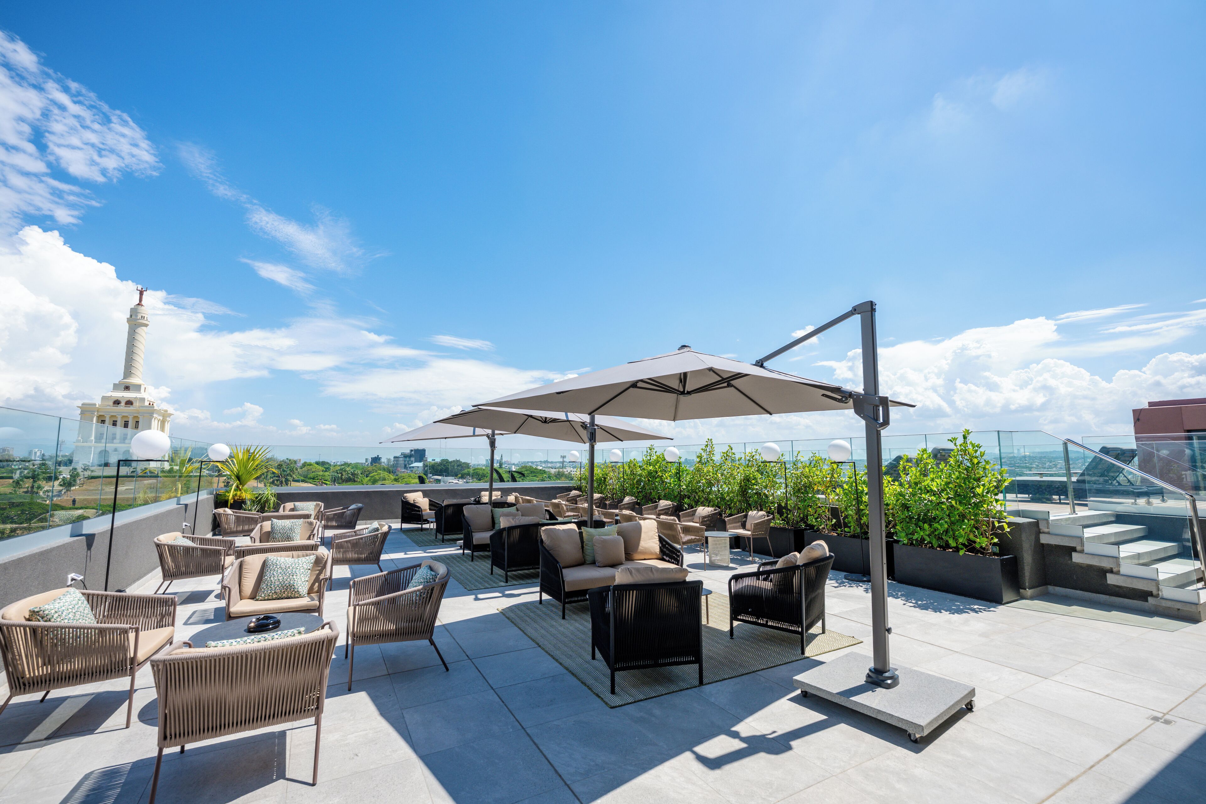 A rooftop terrace with outdoor seating, umbrellas, and a view of a tower.