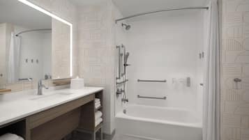 A modern bathroom with a large mirror, a bathtub, and a shower.
