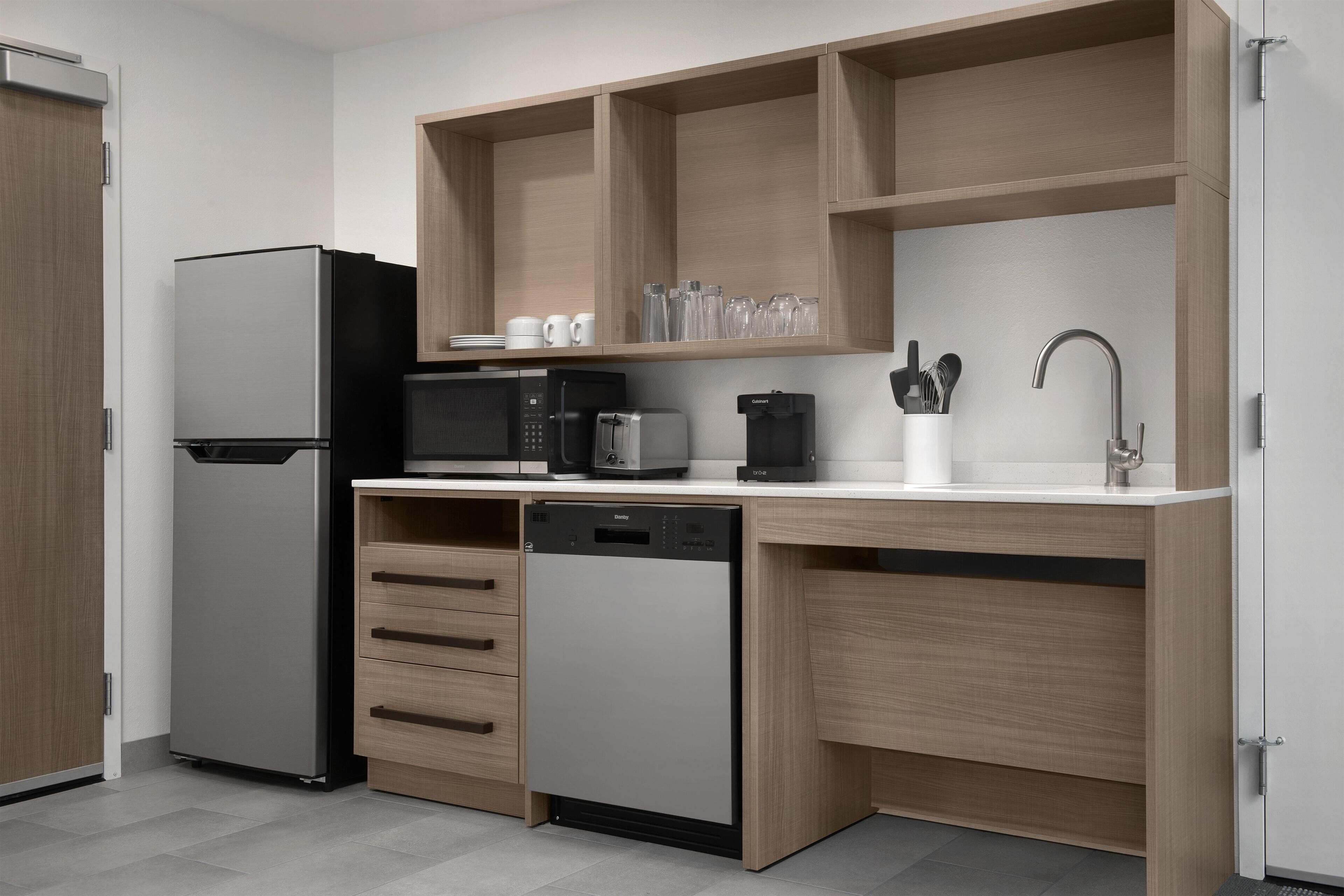 Una cucina moderna completa di lavastoviglie, frigorifero, forno a microonde e macchina per il caffè.