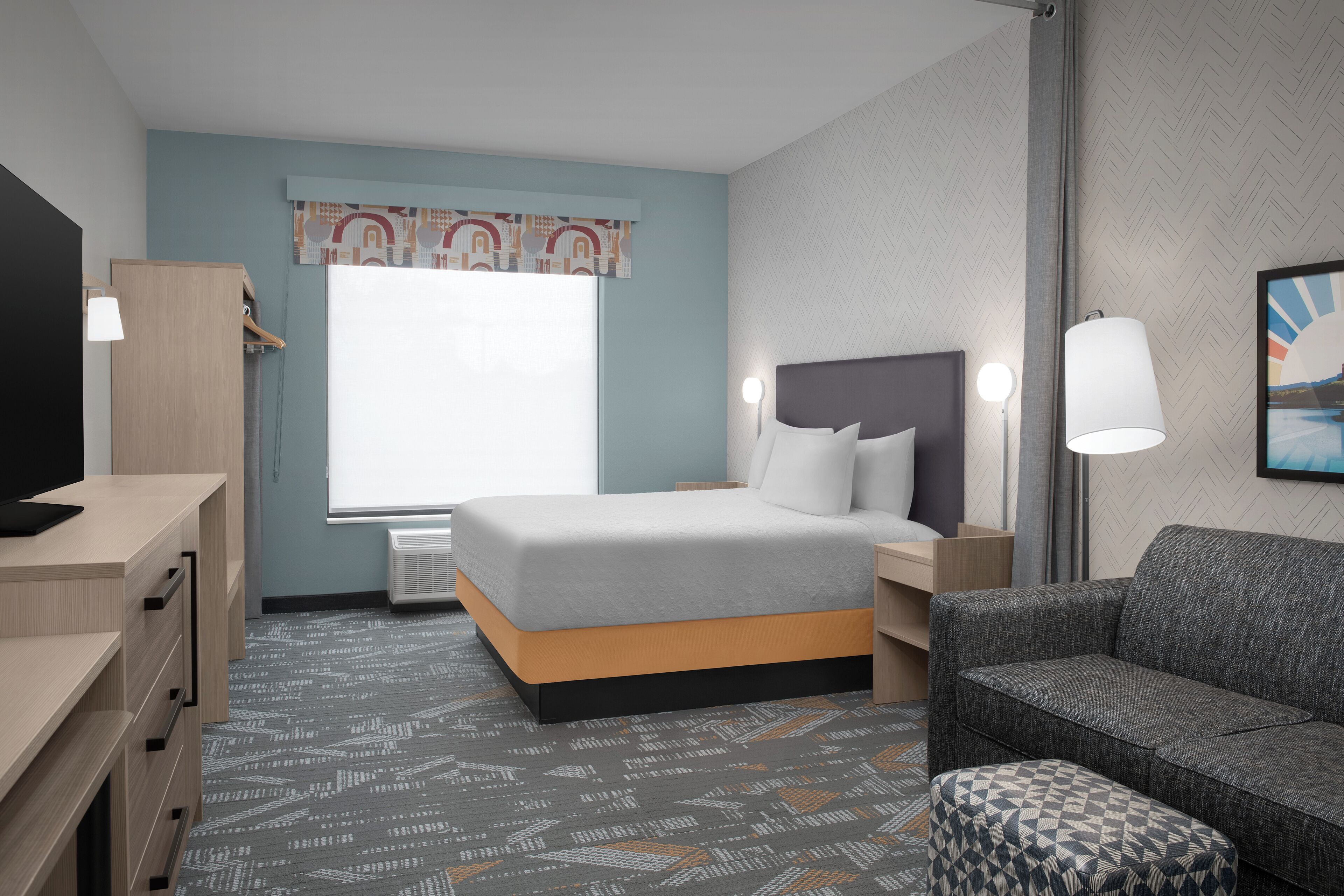 Une chambre d’hôtel avec un lit, un bureau, une chaise et un canapé.