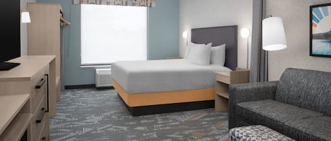 A hotel room with a bed, a desk, a chair, and a sofa.