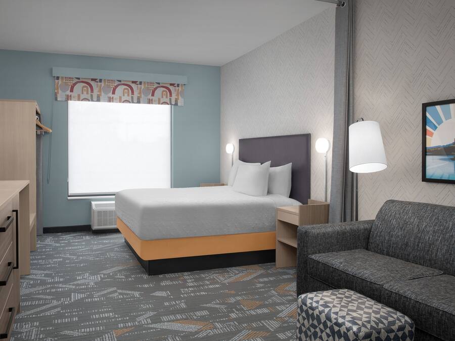 Une chambre d’hôtel avec un lit, un bureau, une chaise et un canapé.