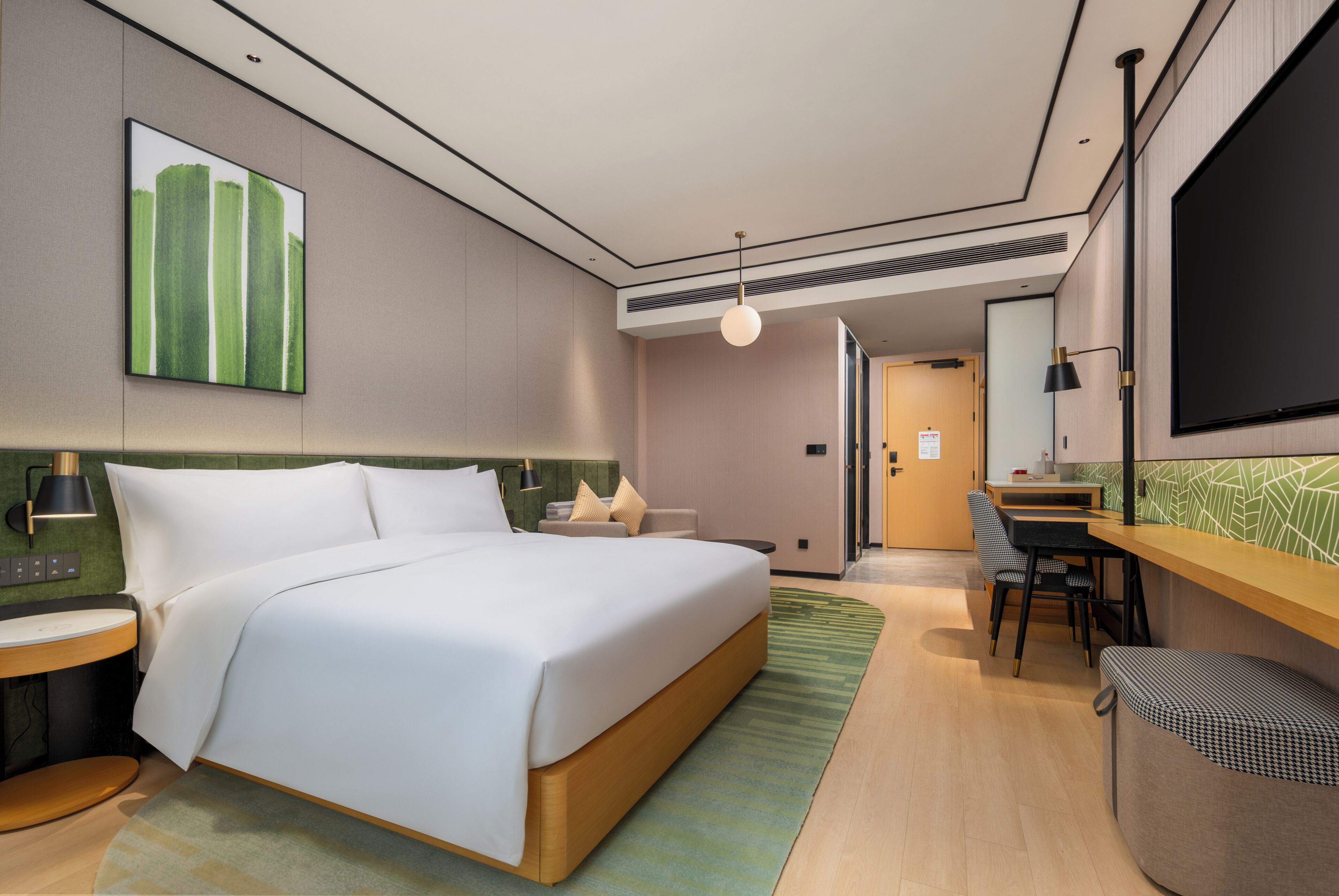 Habitación de hotel con cama, escritorio, silla, televisión y un cuadro en la pared.