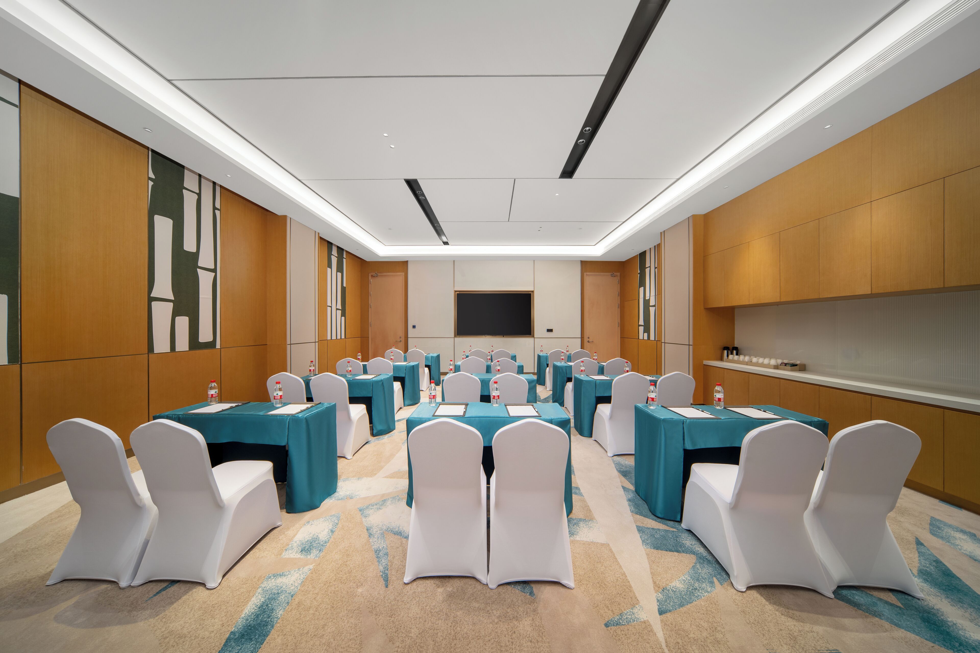 A conference room with multiple tables and chairs, a flat-screen TV, and a carpeted floor.