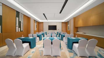 A conference room with multiple tables and chairs, a flat-screen TV, and a carpeted floor.