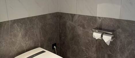 A modern bathroom with a toilet, a trash can, and a towel rack.