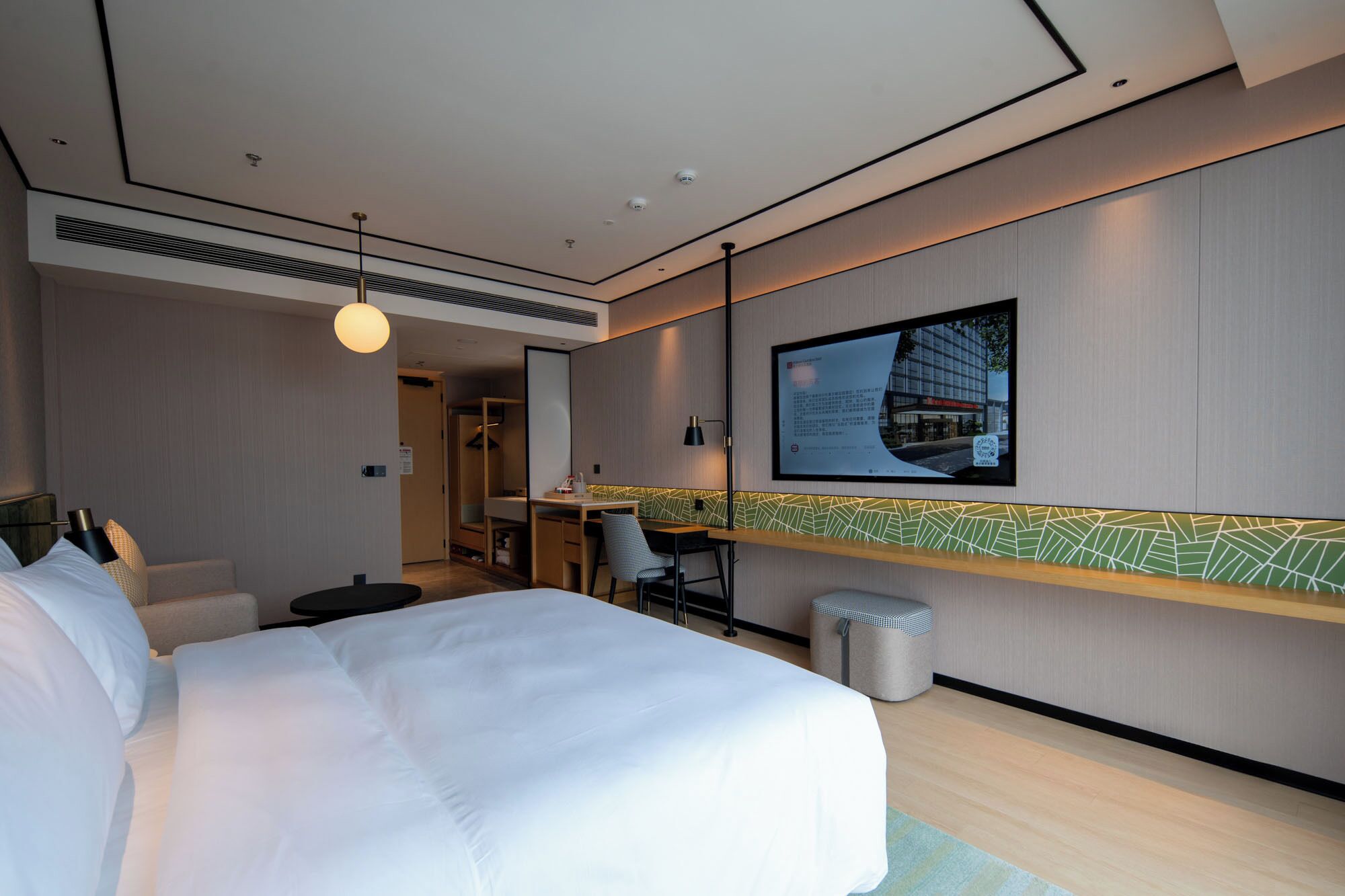 Una camera d'albergo moderna con un letto grande, una scrivania e una TV a parete.