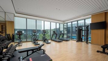 Une salle de sport moderne équipée de tapis de course, de vélos elliptiques et de poids libres.