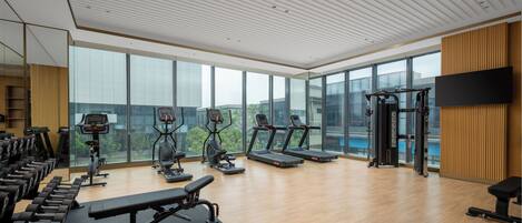 A modern gym with treadmills, elliptical machines, and free weights.