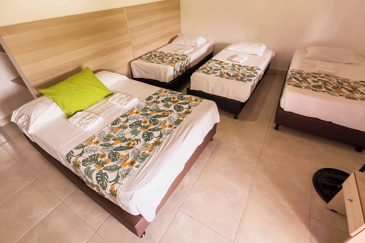 A hotel room with two single beds, a large bed, and a wooden headboard.