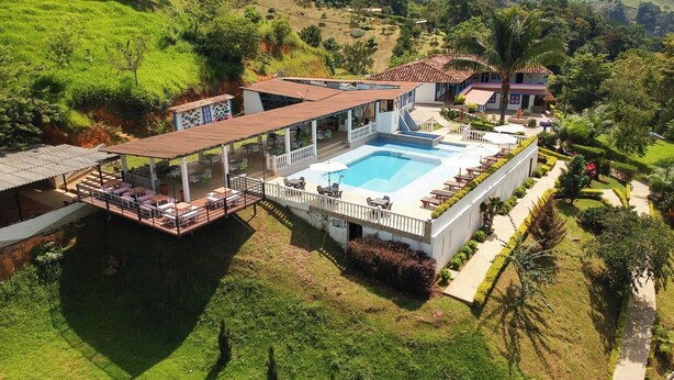 A resort with a large swimming pool, outdoor seating, and lush greenery. - HOTEL JARDIN DEL RIO  (Betania)
