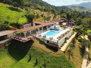 Un resort con una amplia piscina, mobiliario exterior y exuberante vegetación.