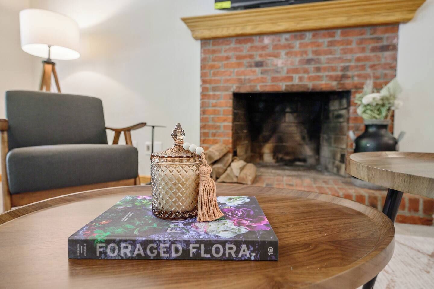 A cozy living room with a fireplace, a round wooden table, and a bookshelf.