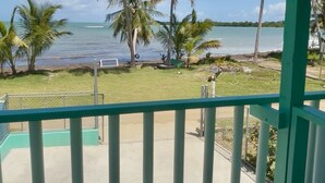 Un balcón con vista a una playa y palmeras.