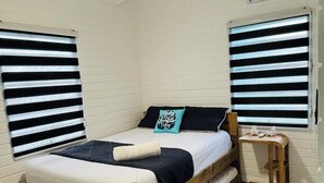 Un dormitorio con una cama de madera, una mesita de noche pequeña y un ventilador de techo.