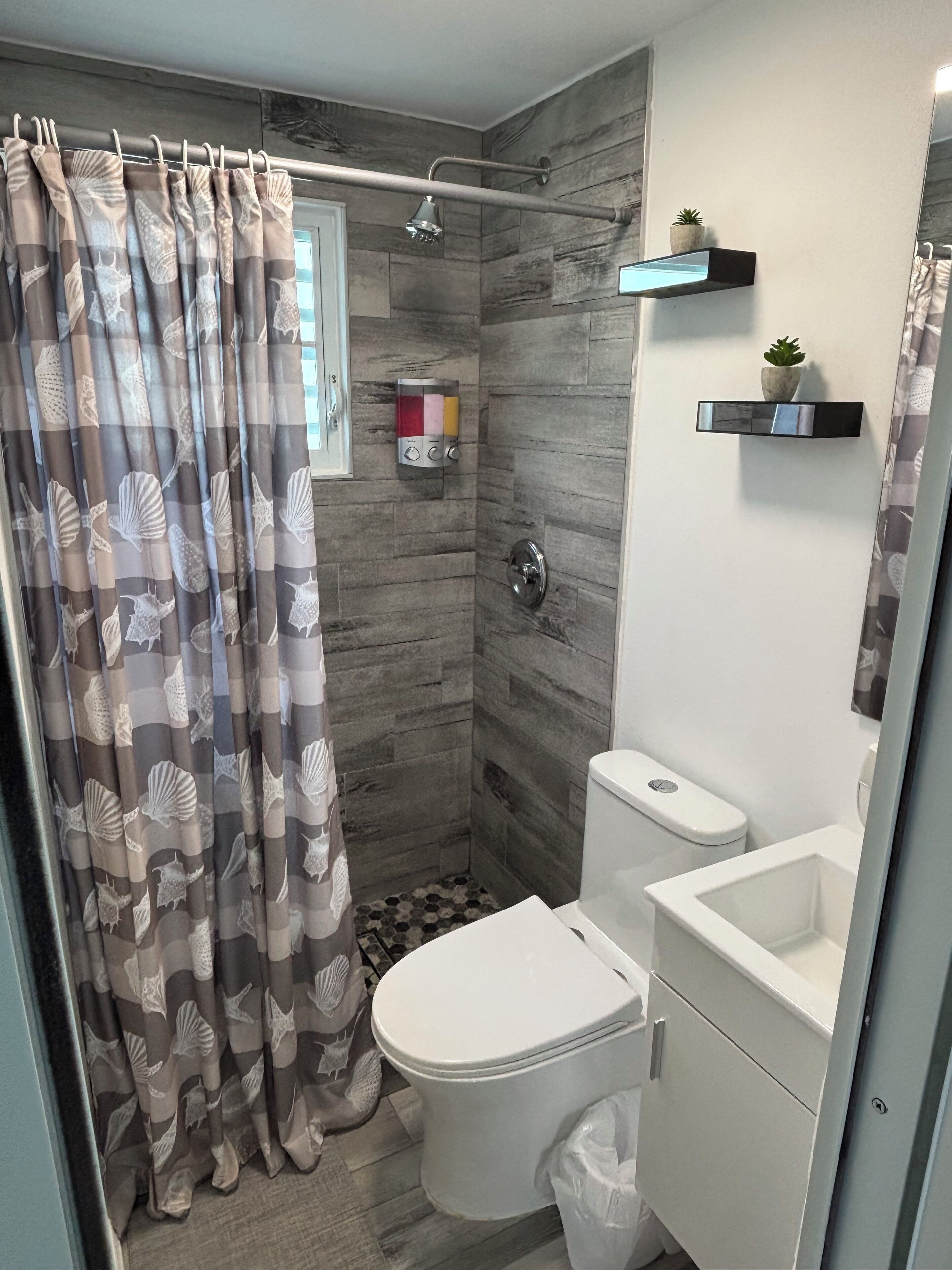 A modern bathroom with a shower, toilet, and sink.
