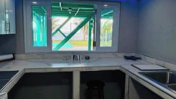 A modern kitchen with a large window, a bar stool, and a sink.