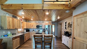 Une cuisine spacieuse avec des meubles en bois, un îlot central et un ventilateur de plafond.