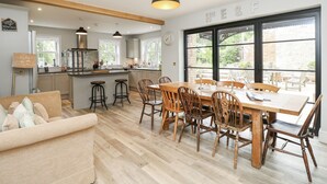 A modern kitchen with a dining area, wooden furniture, and large windows. - Milston (Ventnor)