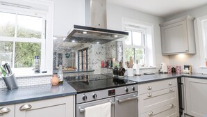 A modern kitchen with a stainless steel stove, oven, and a large window providing natural light. - Milston (Ventnor)