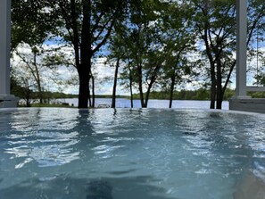 Una piscina infinita con vistas a árboles y una masa de agua.