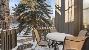 Un patio exterior con una mesa y sillas, un árbol cubierto de nieve y una valla de madera.