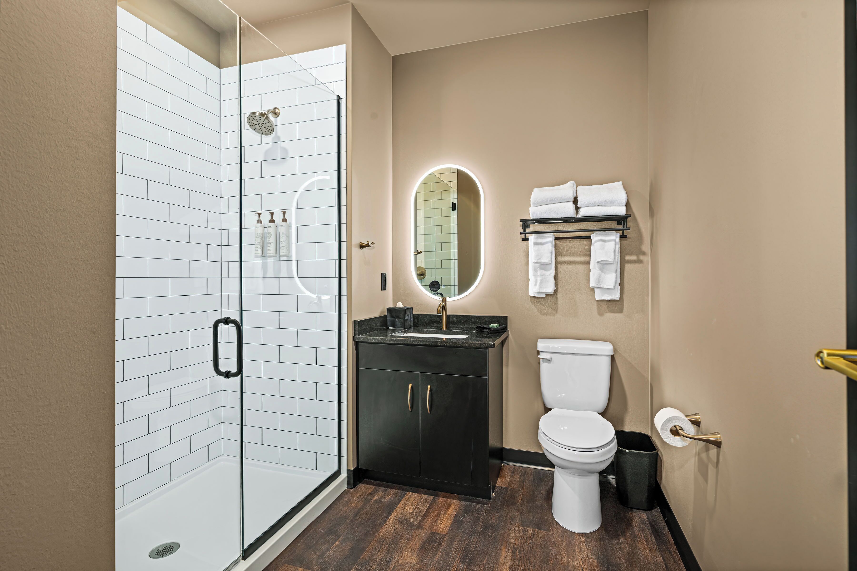 Un baño moderno con cabina de ducha de vidrio, un lavabo con espejo y un inodoro.