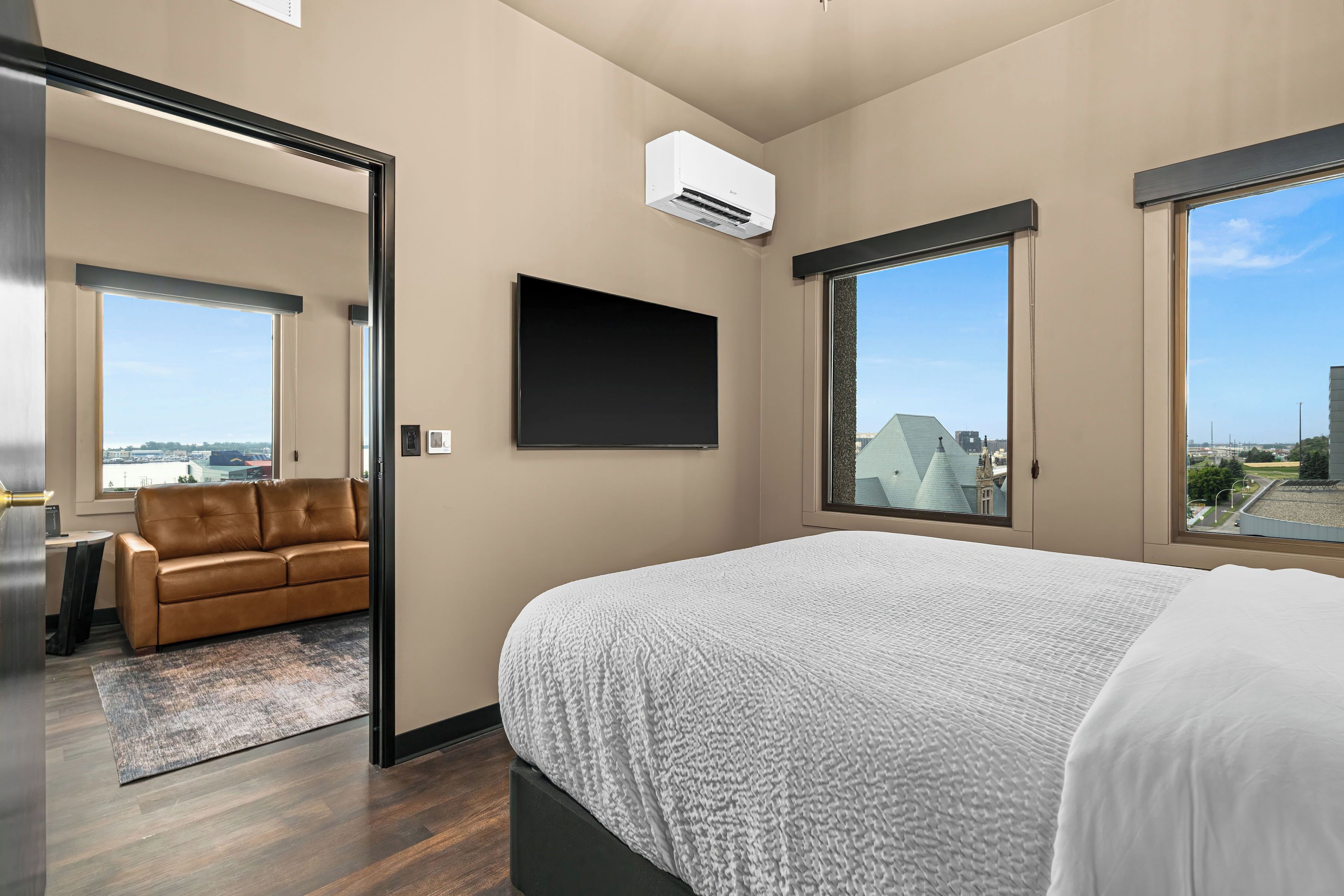 Een moderne hotelkamer met een groot bed, een flatscreen televisie en een bank in de aangrenzende zithoek.