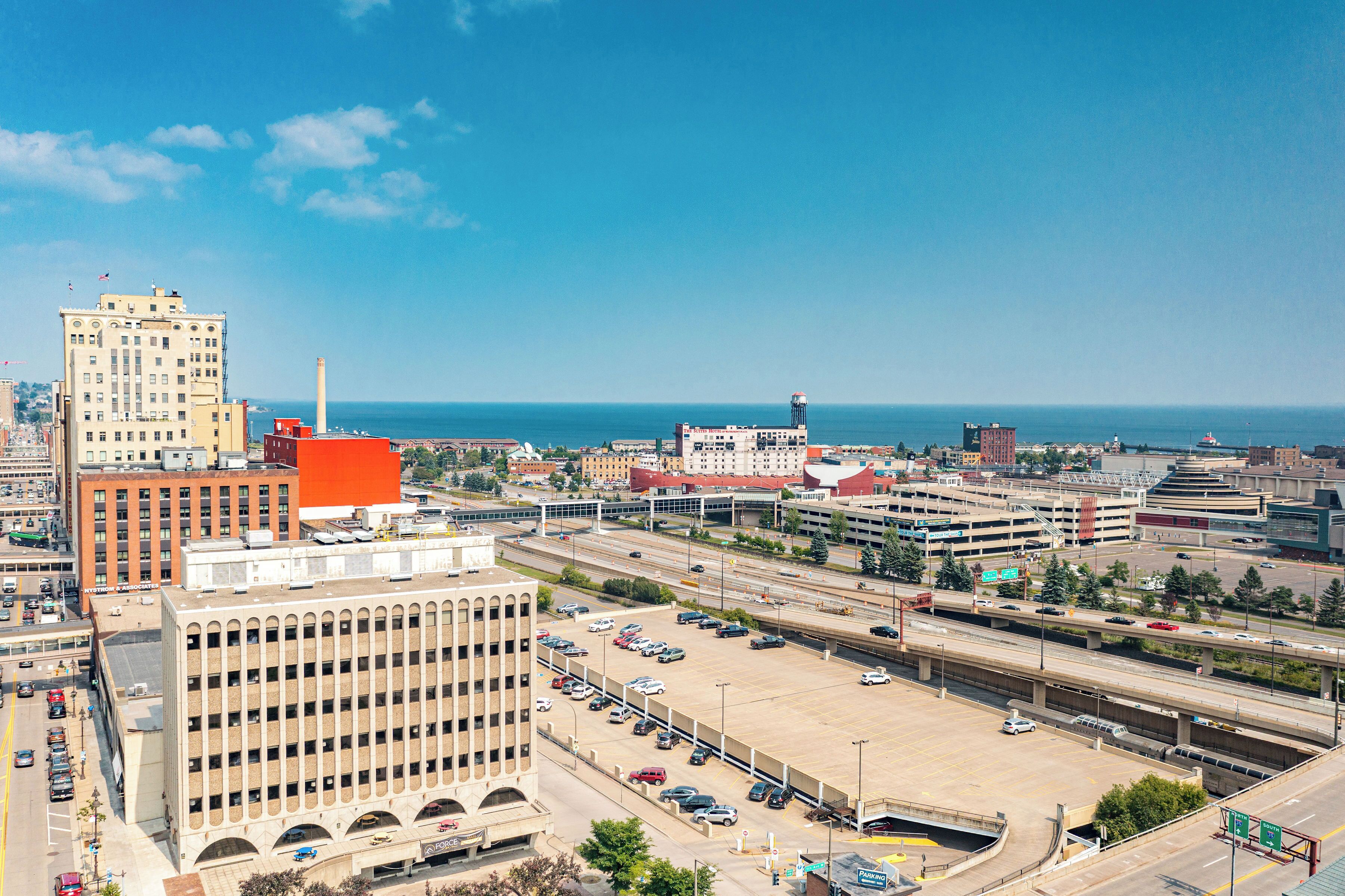Un paisaje urbano con un amplio estacionamiento, varios edificios y vistas al océano.