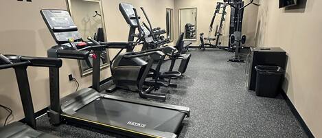 A gym with treadmills, exercise bikes, and weight machines.