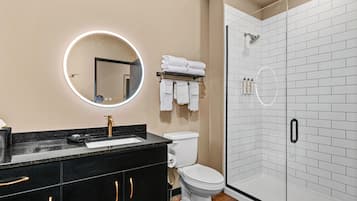 A modern bathroom with a black vanity, white toilet, and a glass-enclosed shower.