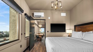 A hotel room with a large bed, a desk, and a view of the city.