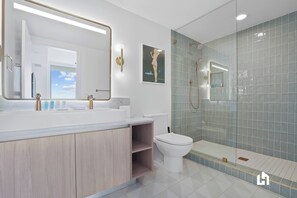 Une salle de bain moderne avec un grand miroir, une douche et des toilettes.