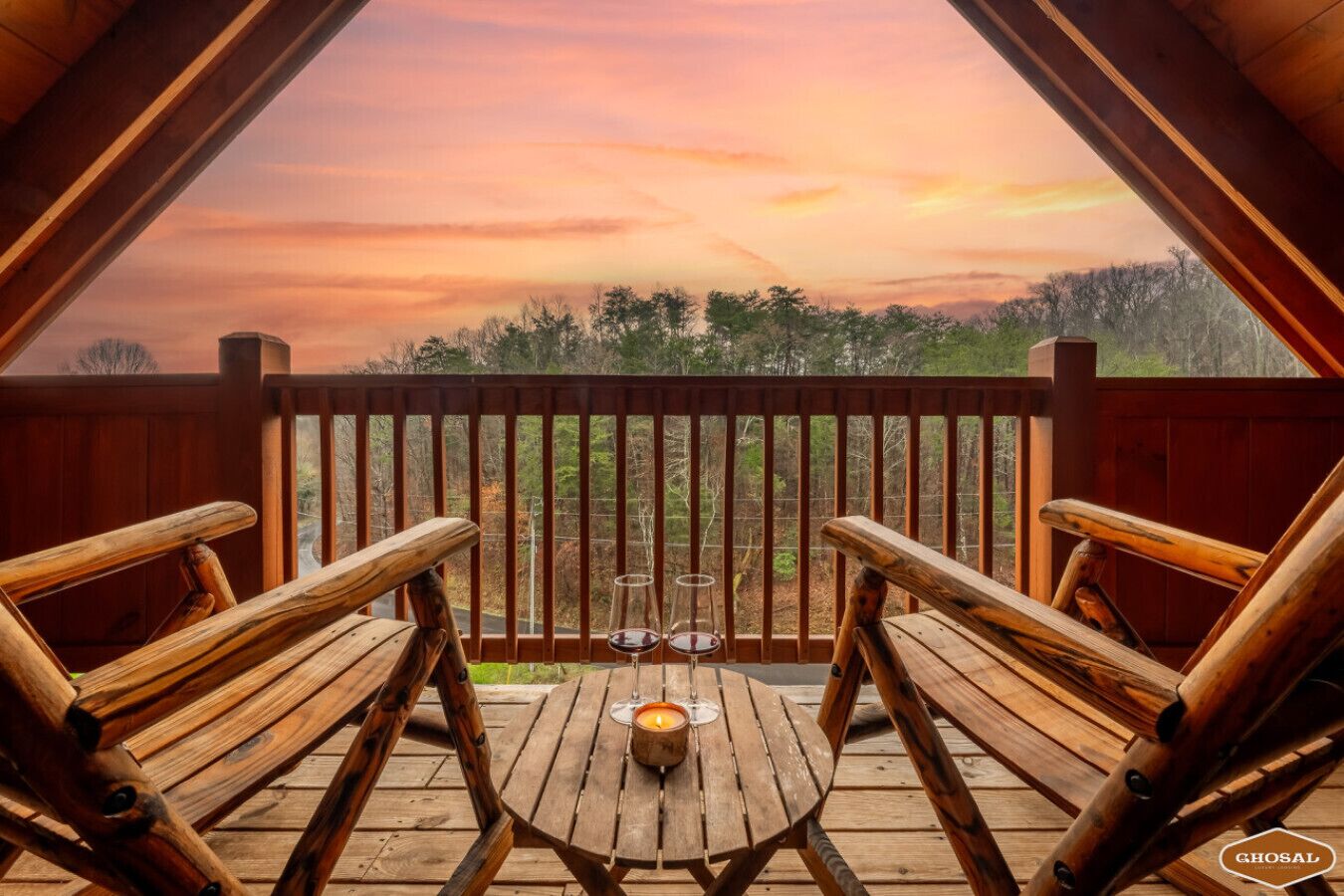 Une terrasse en bois avec deux chaises en bois et une table, un verre de vin et une bougie.