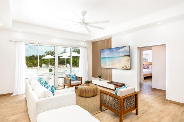A modern hotel room with a large window, a ceiling fan, a flat-screen TV, and a bed.