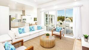 Una sala de estar moderna con un sofá blanco, una mesa de centro redonda y vistas al patio exterior.