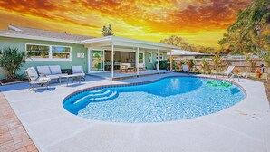 Ein modernes Haus mit Swimmingpool, Sitzgelegenheiten im Freien und einer Terrassenfläche.