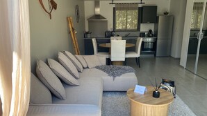 A modern living room with a sectional sofa, a round wooden coffee table, and a dining area with a table and chairs. - 1 bedroom apartment in quiet residence! Peaceful! & Always Sunny! (PROPRIANO)