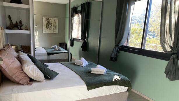 A modern bedroom with a large bed, a bedside table, a mirror, and a window with curtains. - 1 bedroom apartment in quiet residence! Peaceful! & Always Sunny! (PROPRIANO)
