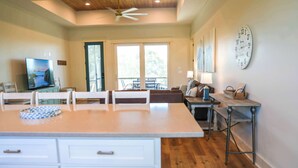 A spacious living area with a large island, a television, and a dining table. - St George Island Home with Private Pool, Pet Friendly (heated/cooled pool for a fee) (Eastpoint)