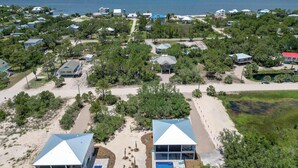 An aerial view of a coastal residential area with multiple houses, a beach, and a pier in the background. - St George Island Home with Private Pool, Pet Friendly (heated/cooled pool for a fee) (Eastpoint)