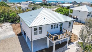 A coastal house with a metal roof, a balcony, and a view of the beach and ocean. - St George Island Home with Private Pool, Pet Friendly (heated/cooled pool for a fee) (Eastpoint)