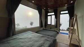 Une chambre avec deux lits, de grandes fenêtres et une vue sur l’extérieur.