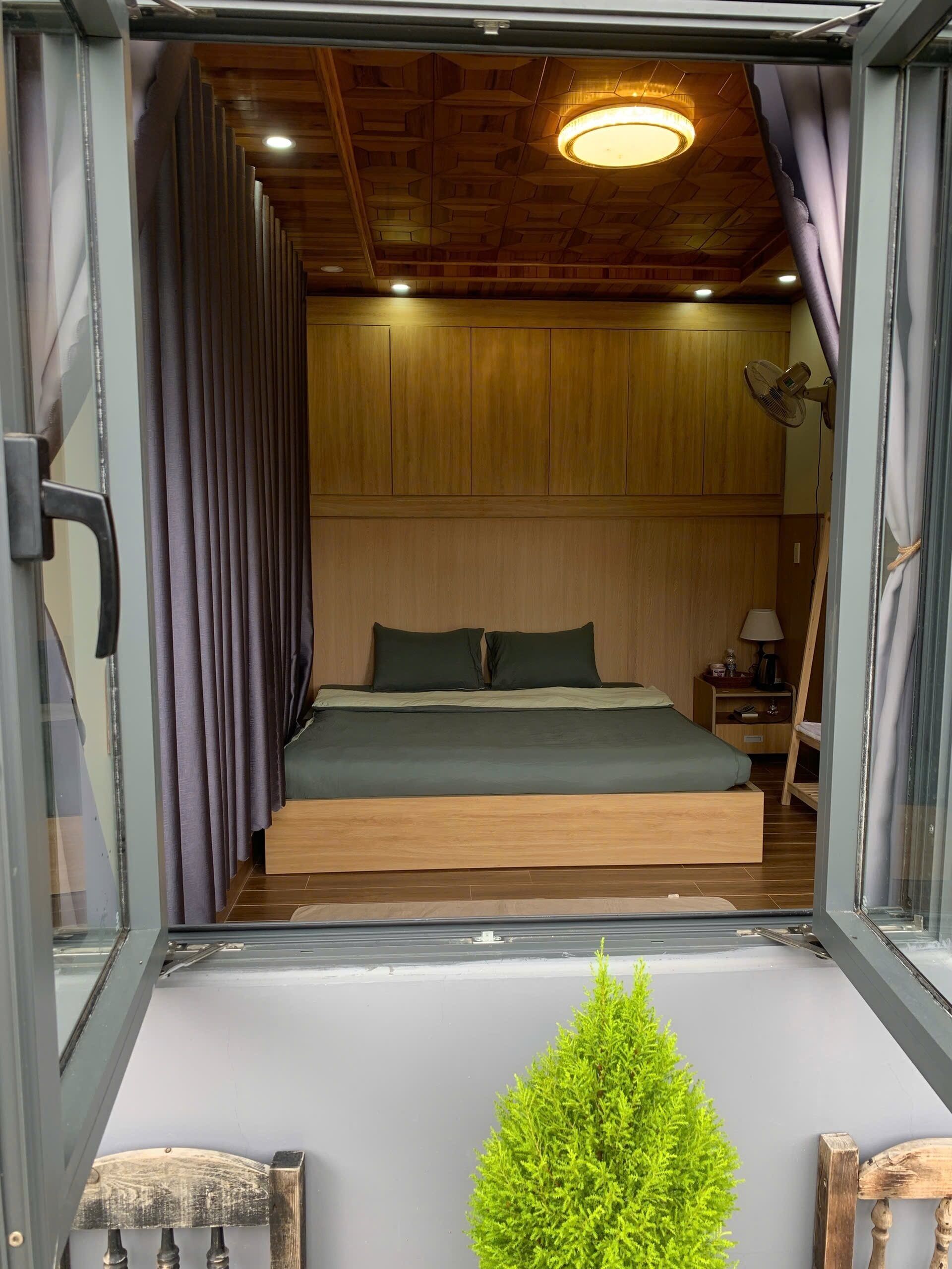 Un dormitorio con techo de madera, una cama con ropa de cama verde, una mesita de noche y una peque ña planta verde.