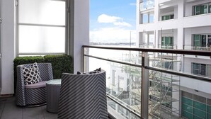 A balcony with wicker furniture, a view of a cityscape, and a building with multiple floors. - Space Style and Comfort (Auckland)